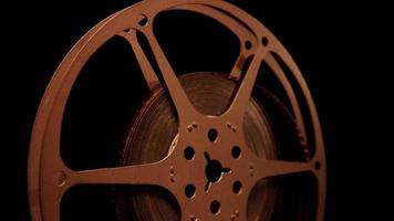 Close up of film reel spinning with front illumination showing a light reflections on dark background in 4K video