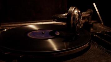 Dark close up shot of classic music player, showing tha needle on vinyl disc with purple label in 4K video