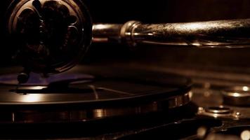 Dark extreme close up of decorated needle playing a vinyl disc on classic record player and weak overhead lighting in 4K video