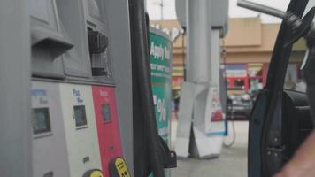 man in tankstation nemen van een mondstuk uit brandstof dispenser video