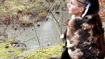 Hermosa mujer vikinga sentada sobre una roca en otoño paisaje natural video