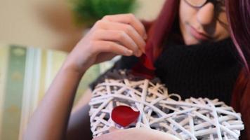 Valentinstag Geschenk. junges Mädchen, das weißes hölzernes Herz mit Rosenblättern hält video