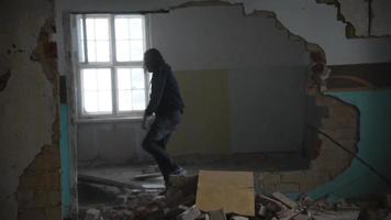 Homme déprimé et fou jette une chaise à travers une pièce dans une vieille maison abandonnée video
