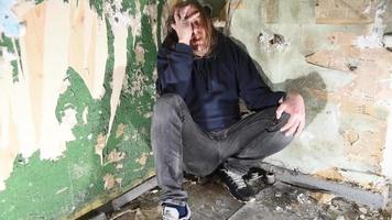 Depressed and angry man is sitting in the corner in an abandoned house video