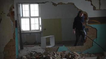 Hombre deprimido y loco lanza una silla a través de una habitación en una vieja casa abandonada video