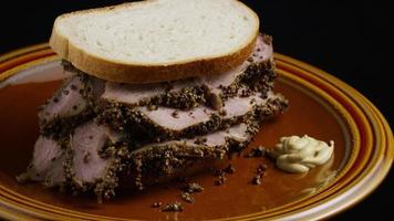 Foto giratoria de un delicioso sándwich de pastrami premium junto a una cucharada de mostaza de Dijon - comida 033
