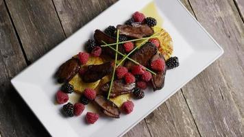 Tir rotatif d'un délicieux plat de bacon de canard fumé avec ananas grillé, framboises, mûres et miel - nourriture 089 video