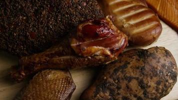 Rotating shot of a variety of delicious, premium smoked meats on a wooden cutting board - FOOD 072