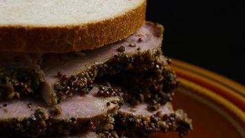 Tir rotatif de délicieux sandwich au pastrami de première qualité à côté d'une cuillerée de moutarde de Dijon video