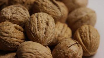 Cinematic, rotating shot of walnuts in their shells on a white surface - WALNUTS 074 video