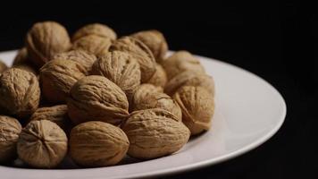 filmische, roterende opname van walnoten in hun schelpen op een wit oppervlak - walnoten 082 video