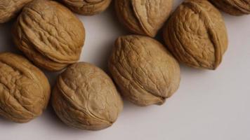 Cinematic, rotating shot of walnuts in their shells on a white surface - WALNUTS 006 video