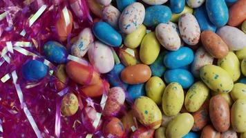 Foto giratoria de coloridos dulces de Pascua sobre un lecho de pasto de Pascua - Pascua 113 video