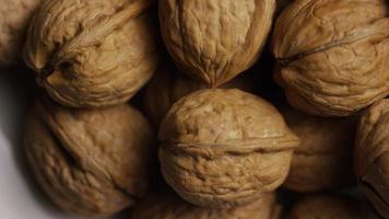 Cinematic, rotating shot of walnuts in their shells on a white surface - WALNUTS 056 video