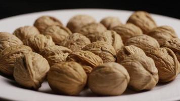 Cinematic, rotating shot of walnuts in their shells on a white surface - WALNUTS 030 video