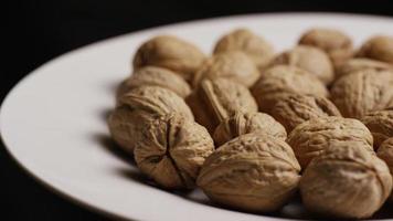 Cinematic, rotating shot of walnuts in their shells on a white surface - WALNUTS 029 video