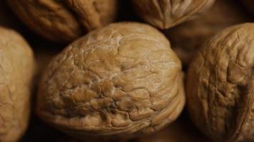 Cinematic, rotating shot of walnuts in their shells on a white surface - WALNUTS 063 video
