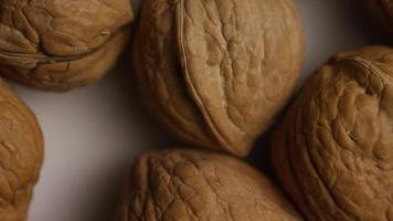 filmische, roterende opname van walnoten in hun schelpen op een wit oppervlak - walnoten 008 video