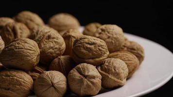 Cinematic, rotating shot of walnuts in their shells on a white surface - WALNUTS 085 video