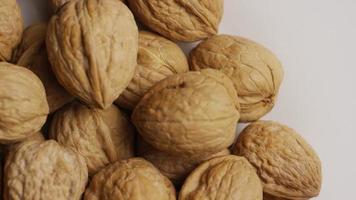 Cinematic, rotating shot of walnuts in their shells on a white surface - WALNUTS 049 video