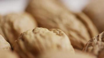 Cinematic, rotating shot of walnuts in their shells on a white surface - WALNUTS 041 video