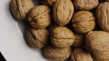 Cinematic, rotating shot of walnuts in their shells on a white surface - WALNUTS 050 video