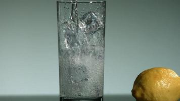 Klare kohlensäurehaltige Flüssigkeit, die in Ultra-Zeitlupe (1.500 fps) in ein mit Eisflüssigkeit gefülltes Glas gegossen und gespritzt wird 019 video