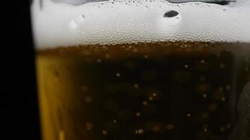 Beer is pouring into glass with foam sliding down side of beer glass video