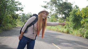 Traveler woman backpacker hitchhiking on the road and walking. video
