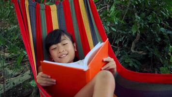 Little girl chilling on hammock and reading a book story video