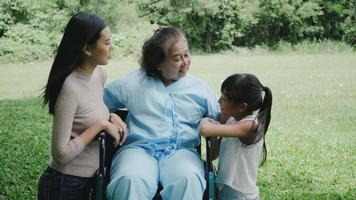 mormor sitter på rullstol med dotter och barnbarn njuta i parken tillsammans video