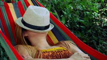 Mujer joven durmiendo en una hamaca con sombrero cubriendo la cara video