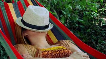 Young woman sleeping in hammock with hat covering face video