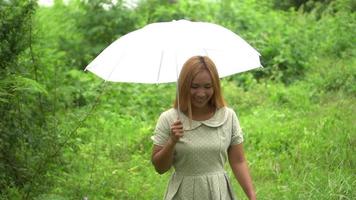 kvinna som går hand som rymmer det vita paraplyet i parken video