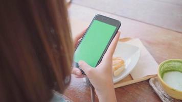 jeune femme asiatique à l'aide de téléphone mobile noir avec écran vert. video