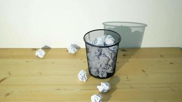 Wide shot of white crumpled paper being thrown into a trash bin video