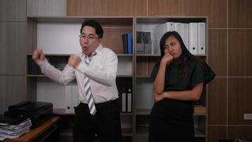 Two joyful colleagues in formal suits dancing cheerfully in the office video