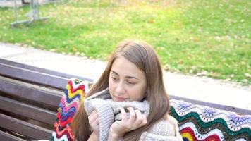 femme se détend sur le banc dans le magnifique parc verdoyant. Mouvement vidéo 4k. jolie fille est assise sur un banc en bois parmi les verts. femme assise sur un banc dans un endroit pittoresque video