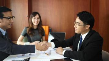 Business partners handshaking after signing contract at office. video