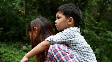 Mother and son piggyback walking in nature. video