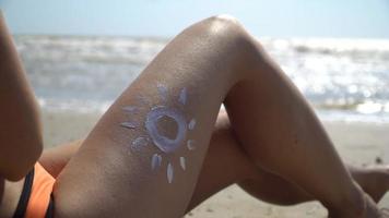 Frau mit gemalter Sonne der Creme auf ihrem Bein gegen das Meer video
