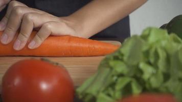 cámara lenta - cerca de mujer haciendo comida sana y cortando zanahoria en tabla de cortar en la cocina. video