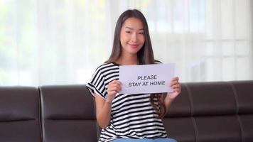 Young Asian woman showing a sign to stay at home video