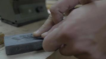 primo piano lavoratore macina uno scalpello su una pietra abrasiva video