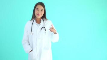 Doctor asiático mujer haciendo el signo de ok sobre fondo azul.
