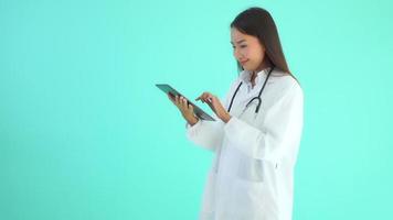 Mujer asiática médico con tableta inteligente sobre fondo azul.