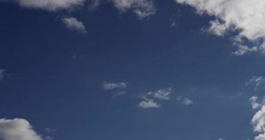 Time lapse of white clouds of different sizes moving away from the camera in 4K video