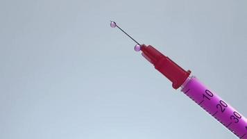 jeringa de insulina inclinada con goteo de líquido rosa video