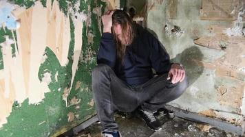 Depressed and angry man is sitting in the corner in an abandoned house video