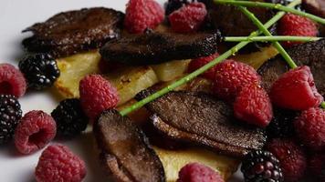 Rotating shot of a delicious smoked duck bacon dish with grilled pineapple, raspberries, blackberries, and honey - FOOD 117 video